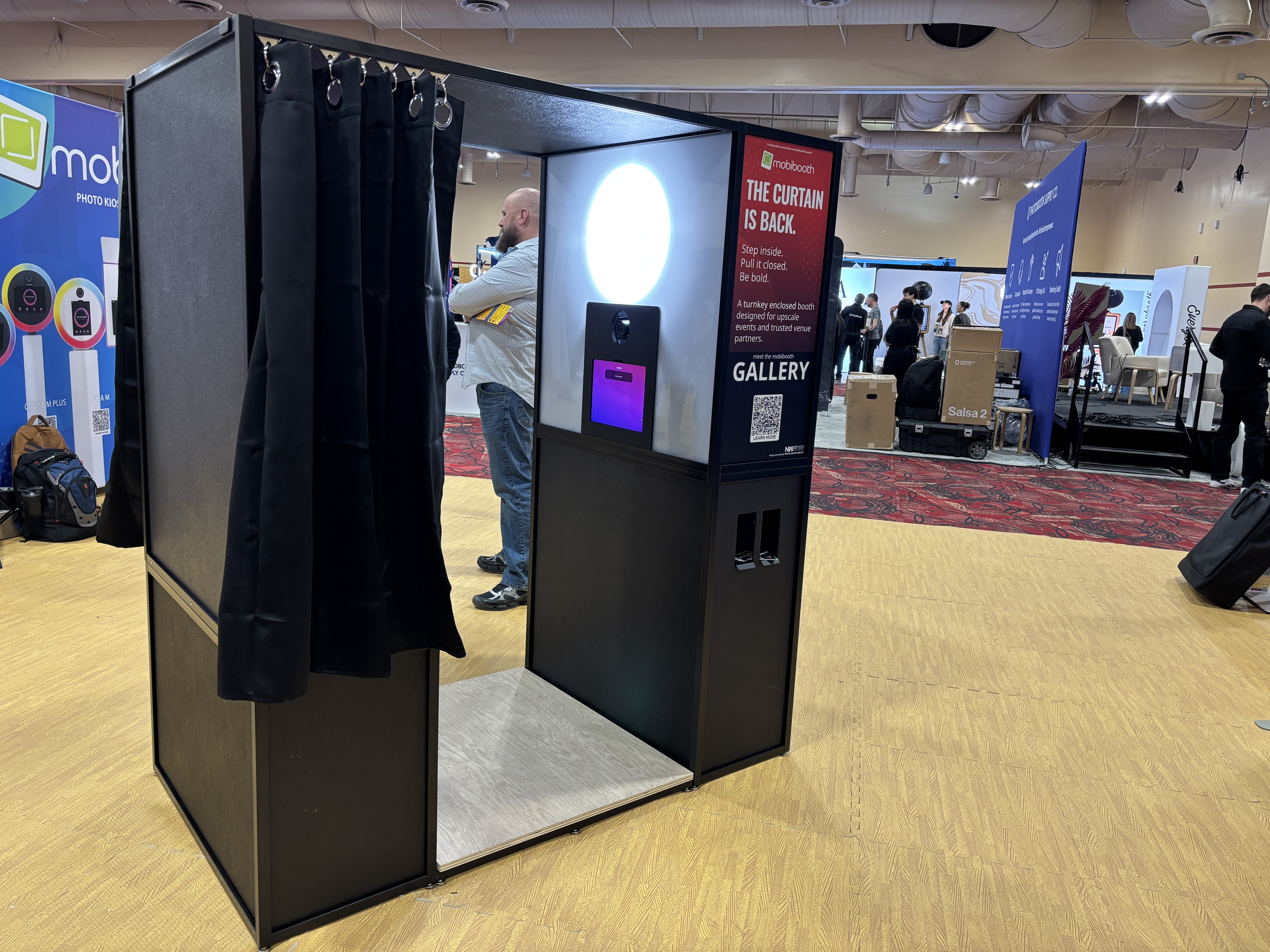 MobiBooth Gallery enclosed photo booth with curtain, ring light, and Pictor tap-to-pay integration on the PBX 2026 show floor