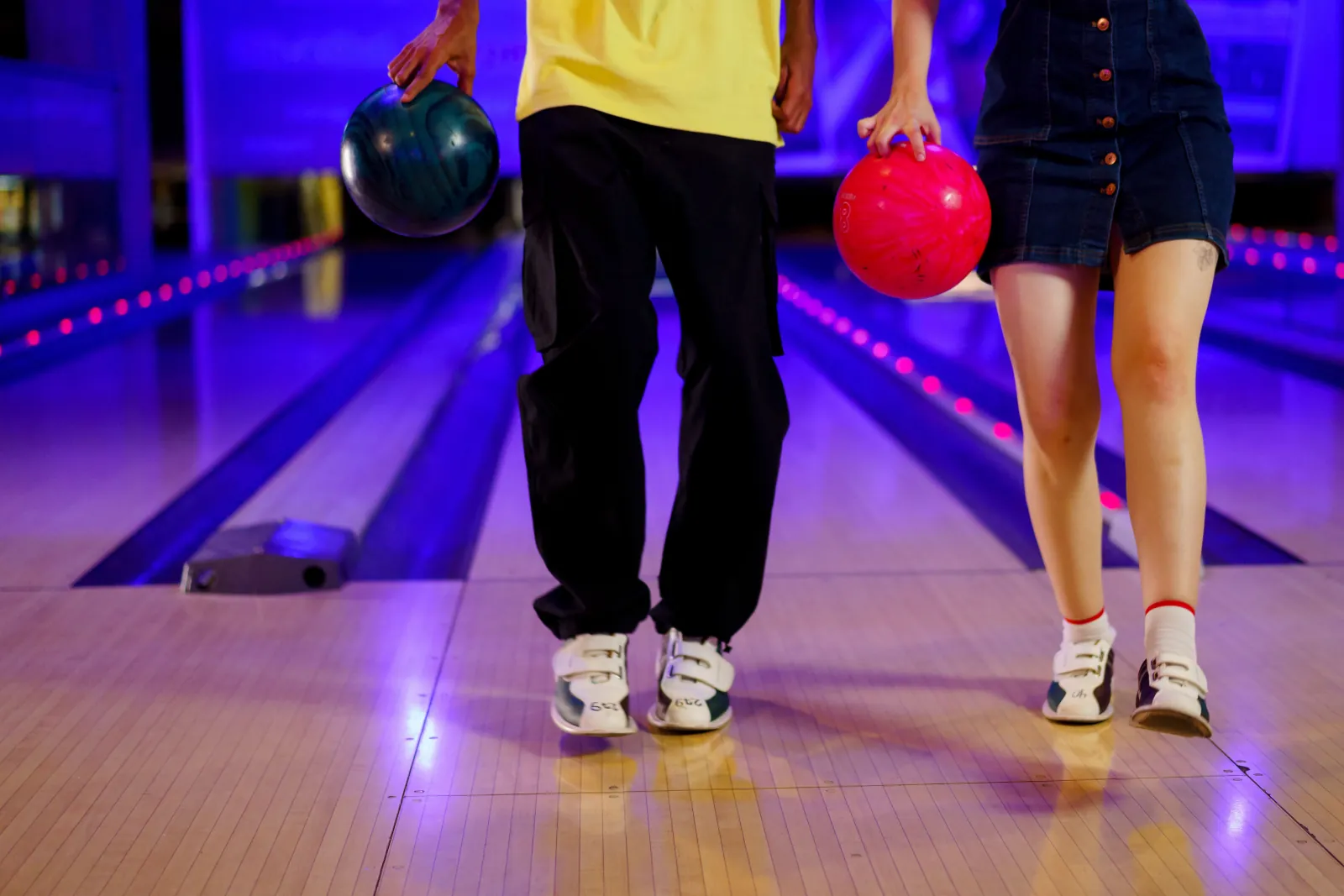 Photo Booth Software for Family Entertainment Centers 2 Two bowlers carrying balls down the approach on illuminated bowling lanes