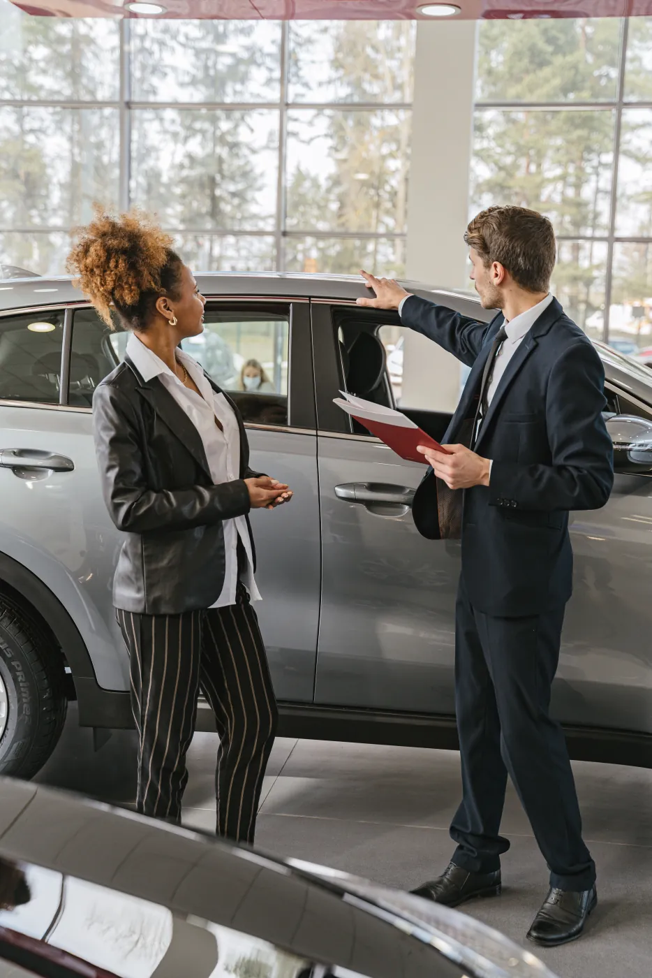 Salesperson showing a customer a vehicle inside a bright dealership showroom