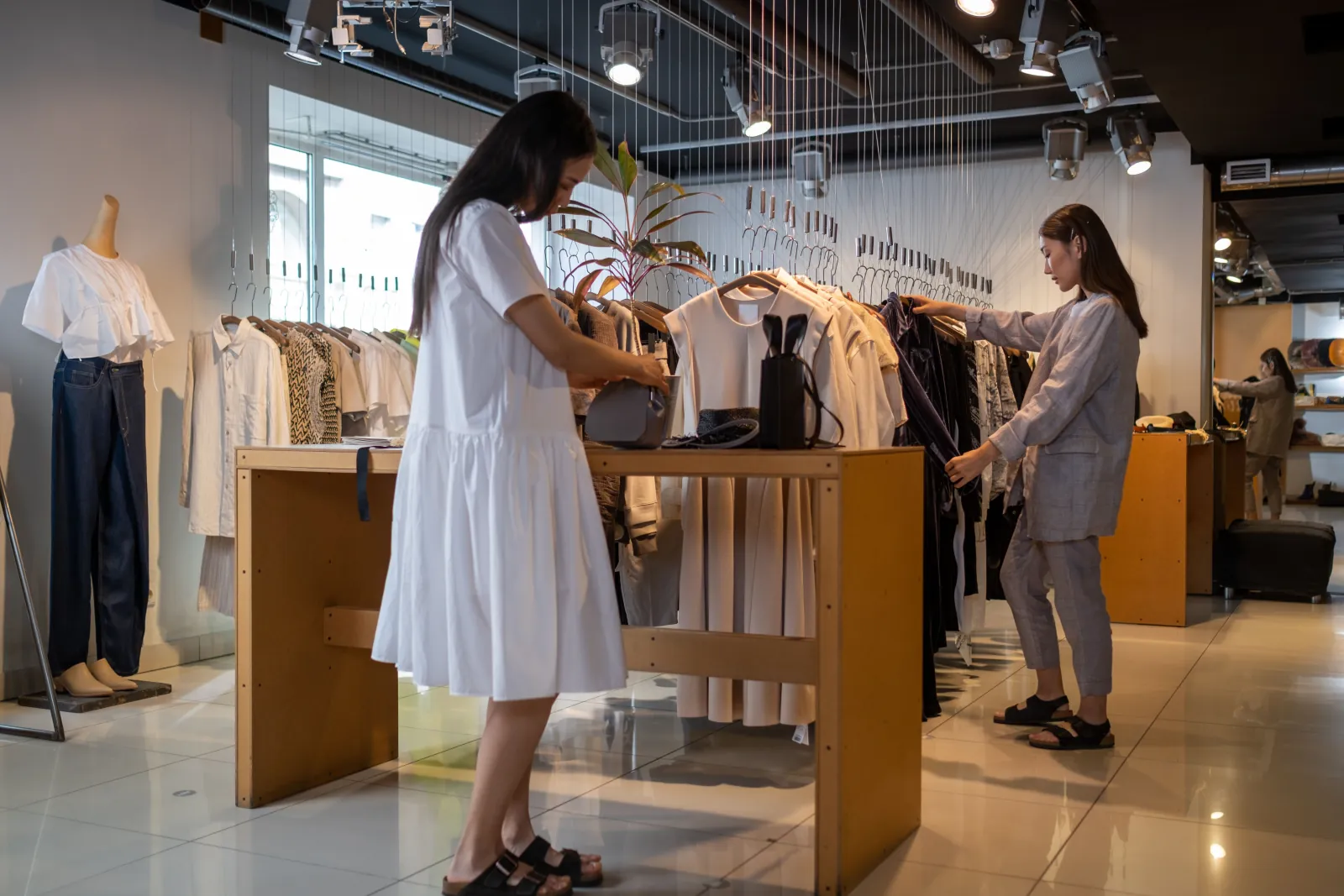 Photo Booth Software for Brand Stores and Pop-Ups 1 Two shoppers browsing clothing racks in a bright modern fashion store