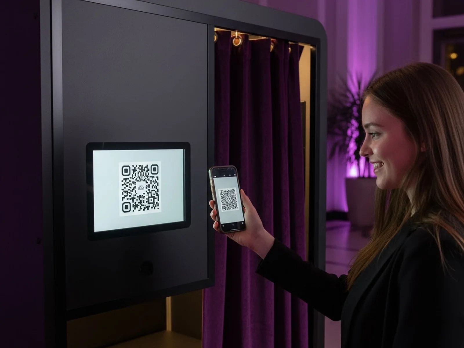 Guest scanning a QR code on the screen of an enclosed photo booth with her phone to pay through Pictor's Paywall