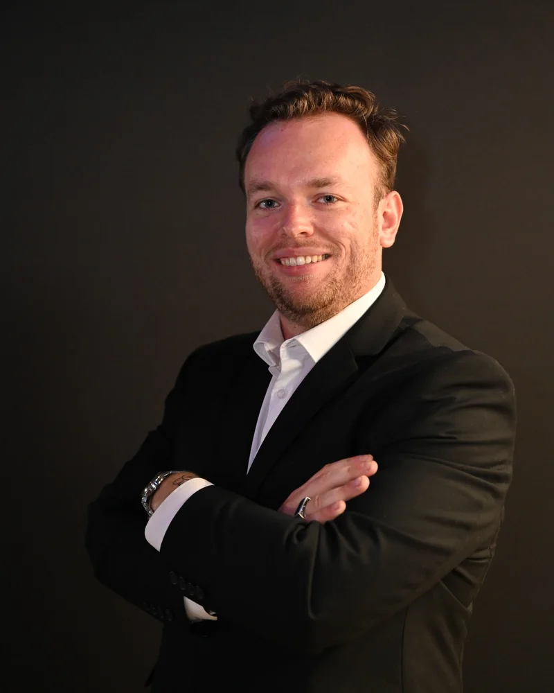 Derek Savickis, Show Producer at Photo Booth Expo, in a dark suit and white shirt with arms crossed