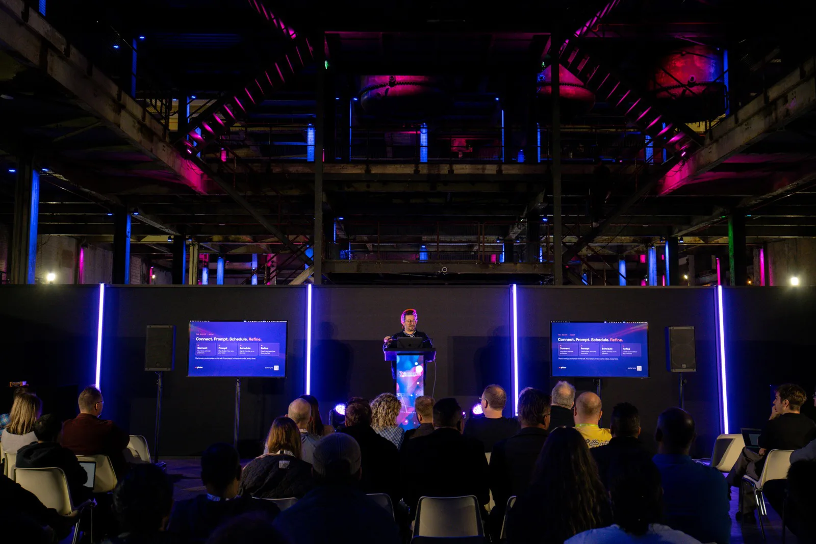 PBX Europe 2026 Recap: Both Talks, Both Decks 11 Nicholas Rhodes at the PBX Europe 2026 keynote with the Connect, Prompt, Schedule, Refine slide on both screens