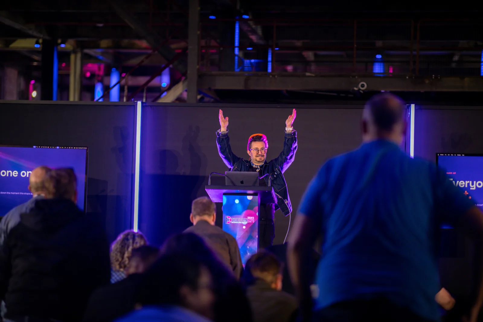 PBX Europe 2026 Recap: Both Talks, Both Decks 3 Nicholas Rhodes with both arms raised at the PBX Europe 2026 keynote podium as the audience stands up